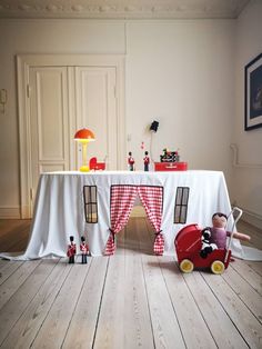 a table with some toys on it and a red wagon in front of the table