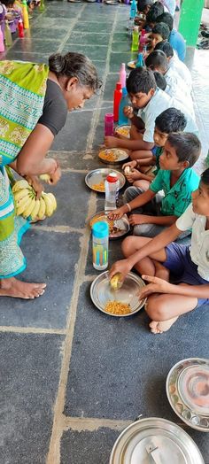 a group of people sitting on the ground with plates of food in front of them