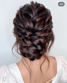 the back of a woman's head with dark brown hair styled into a braid