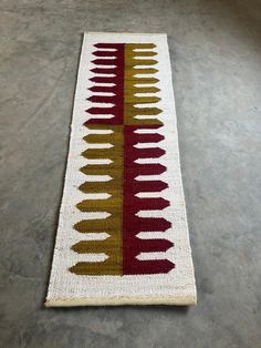 a white rug with red, yellow and brown designs on the bottom is laying on concrete