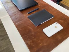 two laptops, an iphone and a pen are sitting on a table in a room