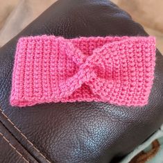 a pink crocheted bow on the back of a brown leather car seat cushion