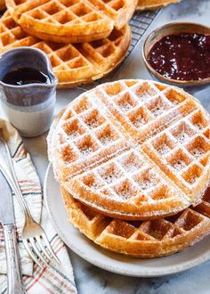 two waffles are on a plate with syrup and condiments next to them