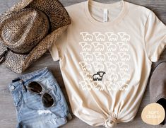 a t - shirt with sheep drawn on it next to some hats and sunglasses,