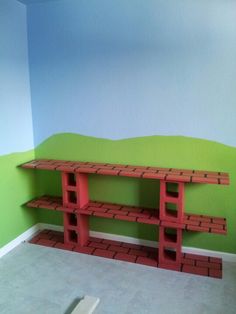 a room with green walls and red shelves on the floor in front of a painted wall