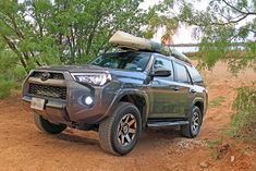 a gray toyota 4runner is parked in the dirt with its kayak on it's roof