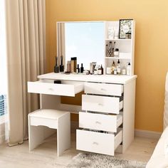 a white desk with drawers and a mirror on it in a room next to a window