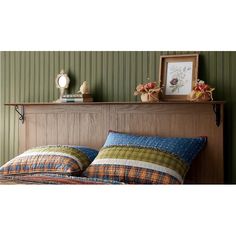 a bed with two pillows on top of it next to a wooden headboard and shelf