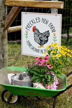 a wheelbarrow filled with flowers next to a sign that reads, pecked hen farm