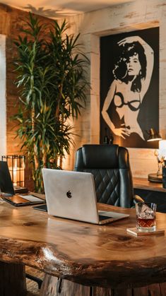 a laptop computer sitting on top of a wooden table next to a chair and potted plant