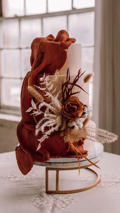 a wedding cake decorated with red and white flowers on a table in front of a window