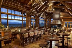 a large wooden bar with lots of chairs and lights hanging from it's ceiling