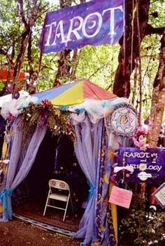 an outdoor tent set up in the woods for a tarot themed birthday party with balloons and streamers