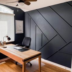 a desk with a laptop on it in front of a wall that is painted black