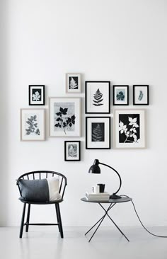 a white room with black and white pictures on the wall, a chair and table