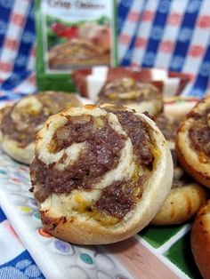 some food is sitting on a table with blue and white checkered cloth, including bread rolls