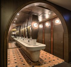 an arched doorway leads to a bathroom with sinks and mirrors on the wall, along with tiled flooring