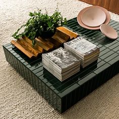 a table that has some plates and plants on top of it in front of a planter