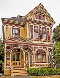 an old victorian style house with red trimmings and yellow paint on the front