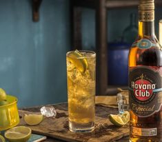 a bottle of havana club next to a glass filled with ice and limes on a table