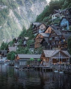 a village on the side of a mountain next to a body of water with boats in it