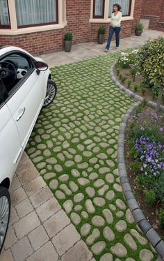 a white car parked in front of a house next to a garden with purple flowers