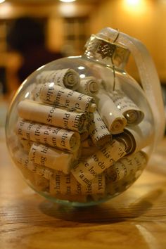 a glass ornament filled with lots of rolled up paper on top of a wooden table