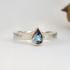 a close up of a ring with a blue topazte in the center on a white background