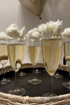 five champagne glasses filled with white wine on a wicker platter, ready to be served