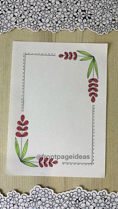 a white paper with red flowers and green leaves in the center on a wooden table