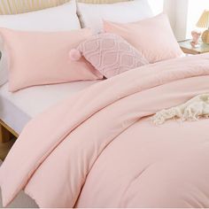 a bed with pink sheets and pillows in a bedroom