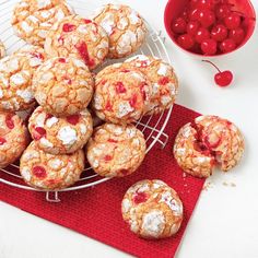 a plate full of cookies and cherries next to a bowl of cherries