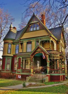 an old victorian style house with green trim on the front porch and red trim on the roof