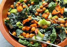 a bowl filled with vegetables and grains on top of a wooden table next to a fork