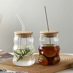 two mason jars filled with water and lemons on a cutting board next to each other