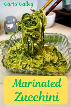 the pasta is being cooked in a glass dish with chopsticks and green sauce