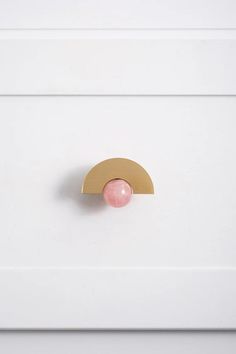 a close up of a drawer with a pink ball on the top and gold trim