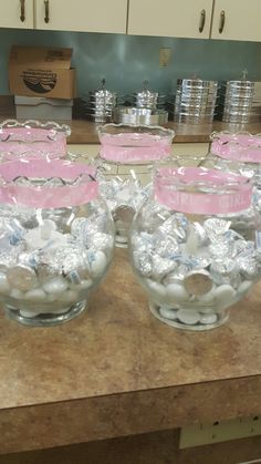 several clear bowls filled with candy sitting on top of a wooden counter in a kitchen