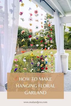 an outdoor area with white curtains and flowers hanging from the ceiling, in front of a gazebo