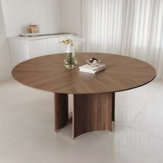 a wooden table sitting in the middle of a living room next to a white wall