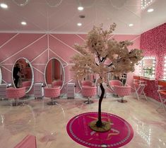 the interior of a salon with pink chairs and mirrors on the walls, trees in the center