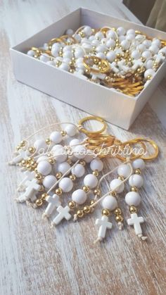 a box filled with white beads and gold colored rings sitting on top of a wooden table