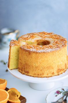 a cake is sitting on a plate next to sliced oranges