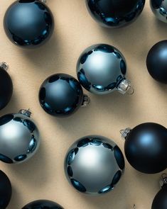 many black and silver ornaments are arranged on a table top, with one blue ornament in the middle