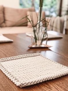 a crocheted placemat sits on a wooden table next to a potted plant