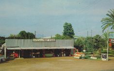 an old photo of a small store in the middle of a dirt lot with palm trees