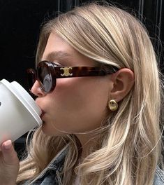 a woman drinking out of a white cup