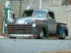 an old truck is parked in front of a gas station