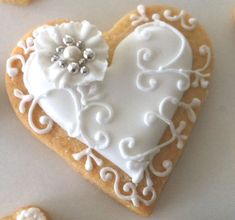 a heart shaped cookie with white icing and flowers on it, surrounded by cookies