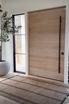 a white vase sitting on top of a rug next to a wooden door and window